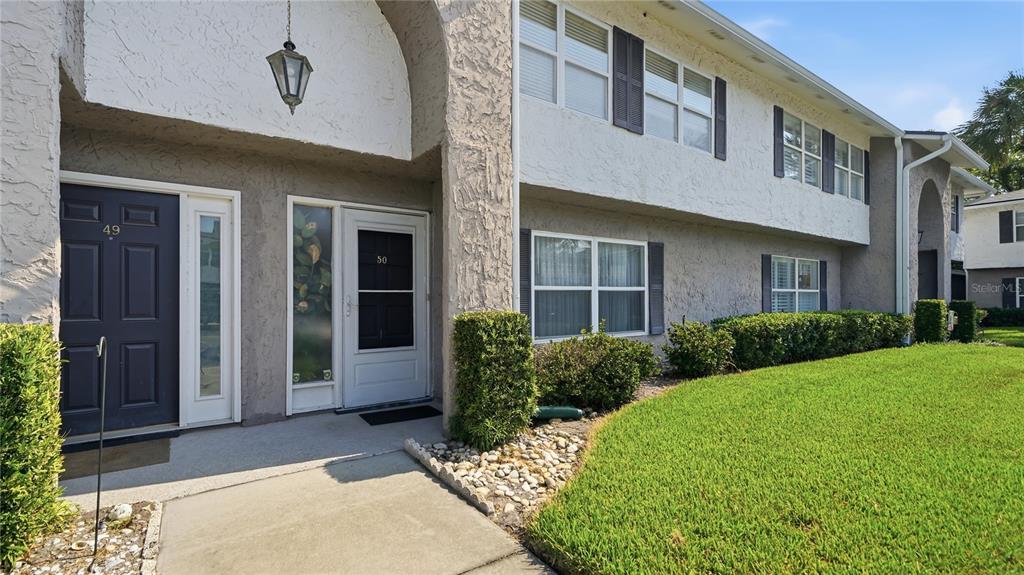 The exterior of a two-story townhouse features a concrete walkway, two front doors, and landscaping — 695 A1A N UNIT 50, PONTE VEDRA BEACH, FL