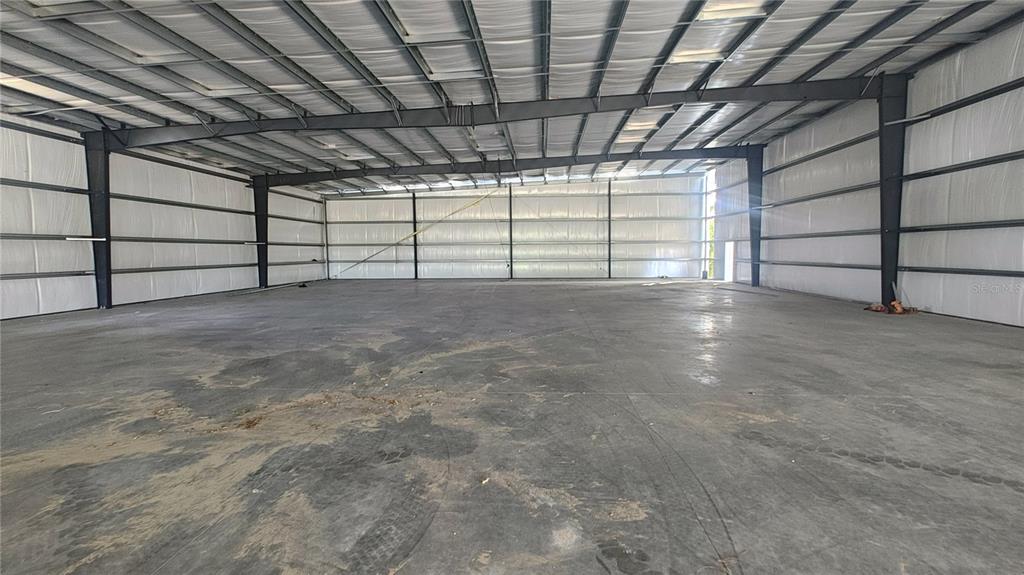 A metal warehouse building under construction stands on a sandy lot with workers present — 12142 SE COUNTY 484 HIGHWAY, BELLEVIEW, FL