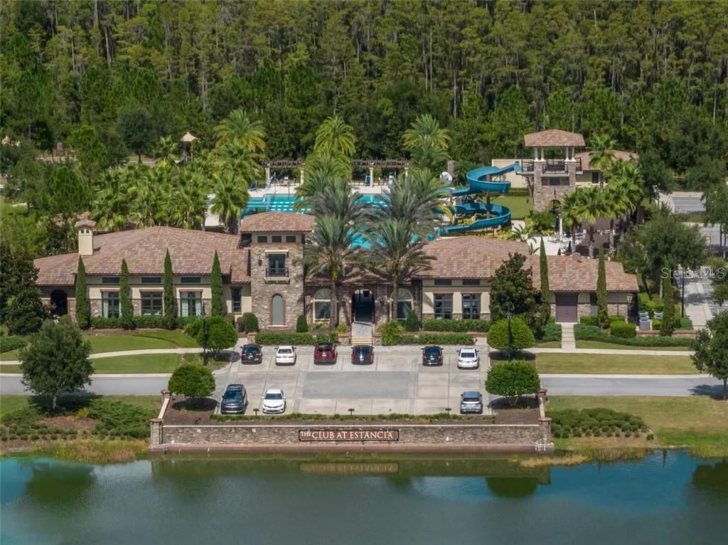 An aerial view of a clubhouse with a pool, water slide, and parking lot — 4887 ISOLA COURT, WESLEY CHAPEL, FL