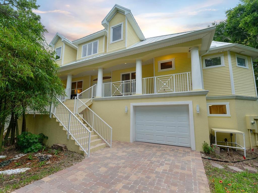A yellow two-story house with a white garage door, front porch, and exterior staircase — 110 OCEAN WAY DRIVE, PONCE INLET, FL
