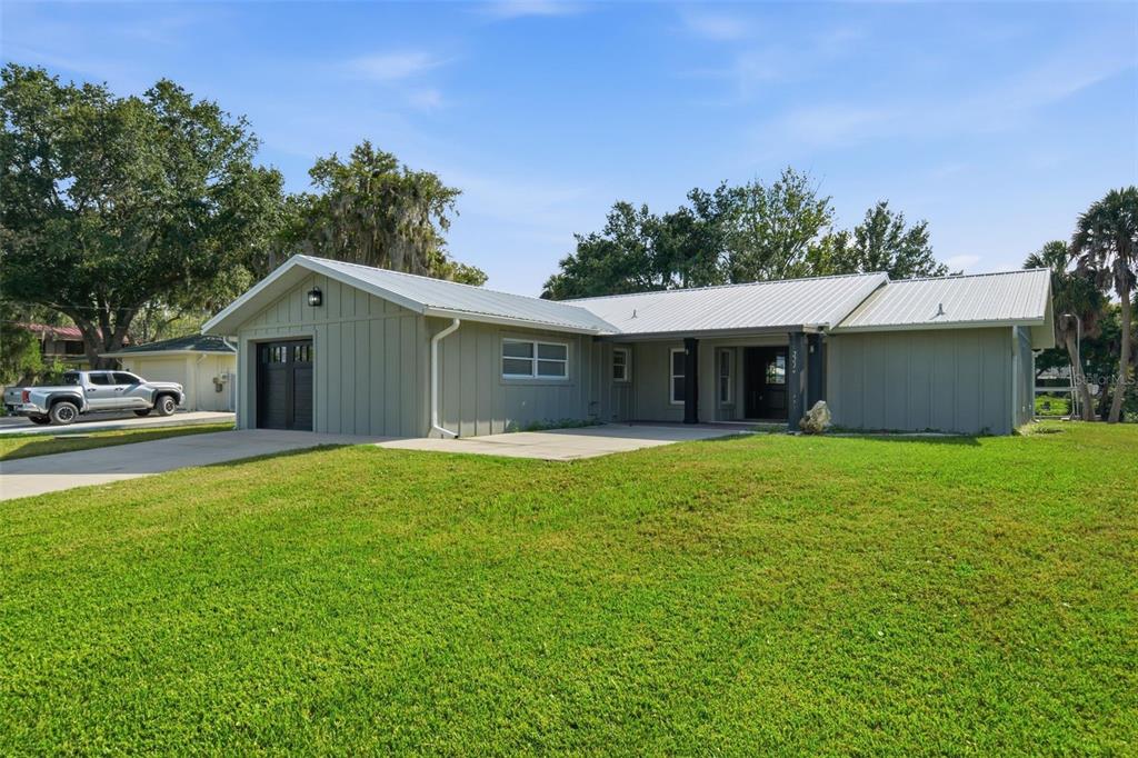 A single-story house with light green vertical siding, a metal roof, and an attached garage — 2236 N WATERSEDGE DRIVE, CRYSTAL RIVER, FL