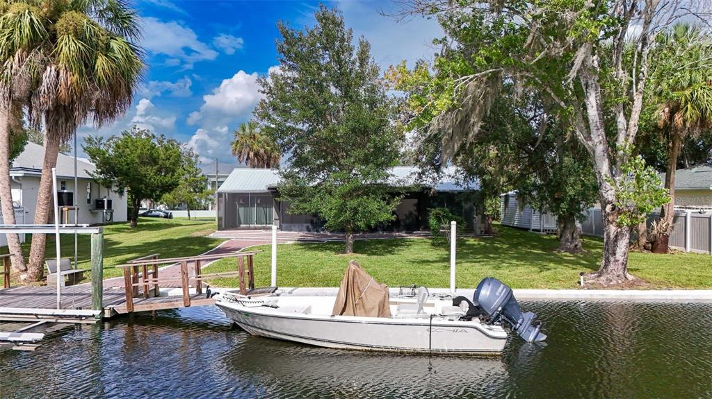 A white motorboat is docked in a canal in front of a house with a lawn — 2236 N WATERSEDGE DRIVE, CRYSTAL RIVER, FL