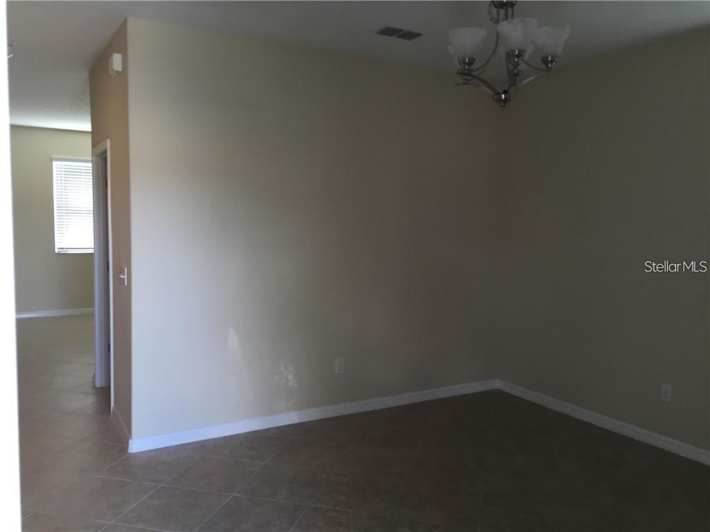 An empty room with beige walls, tile flooring, and a hanging light fixture — 13048 GARRIDAN AVENUE, WINDERMERE, FL
