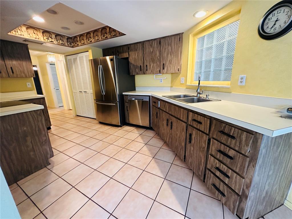 A kitchen features wood-grain cabinets, stainless steel appliances, a glass block window, and tiled flooring — 2361 ORANGESIDE ROAD, PALM HARBOR, FL
