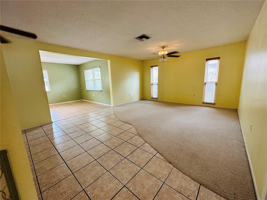 A living room features a mix of beige tile and carpeted flooring with yellow walls — 2361 ORANGESIDE ROAD, PALM HARBOR, FL