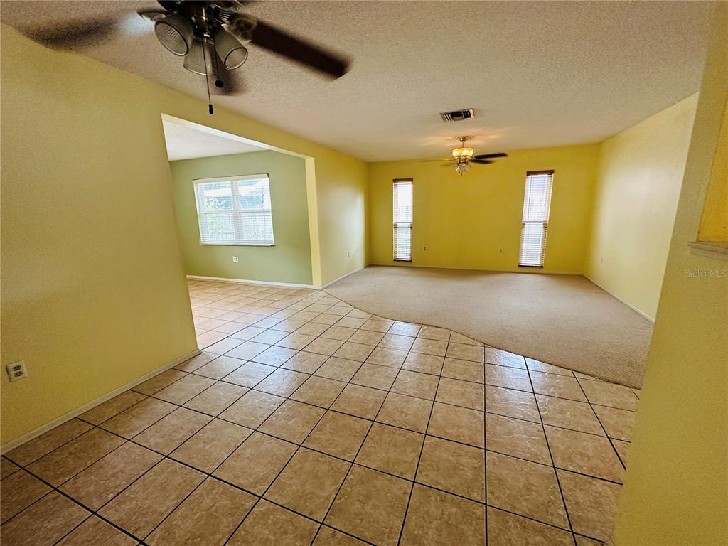 An open-concept living area features tiled flooring in the foreground and carpet in the back — 2361 ORANGESIDE ROAD, PALM HARBOR, FL