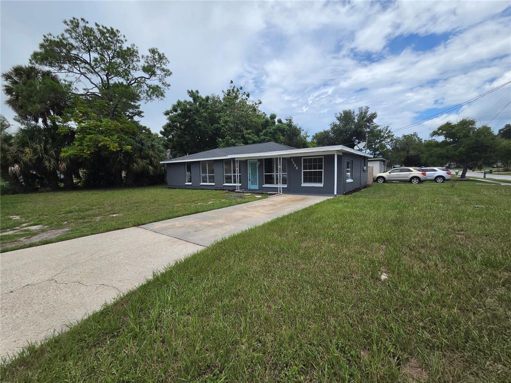 A single-story gray house with a light blue front door and a concrete driveway — 1500 CREST AVENUE, LEESBURG, FL