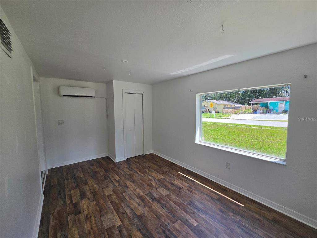 A room with wood-look flooring, a window seat with blue panels, and a doorway — 1500 CREST AVENUE, LEESBURG, FL