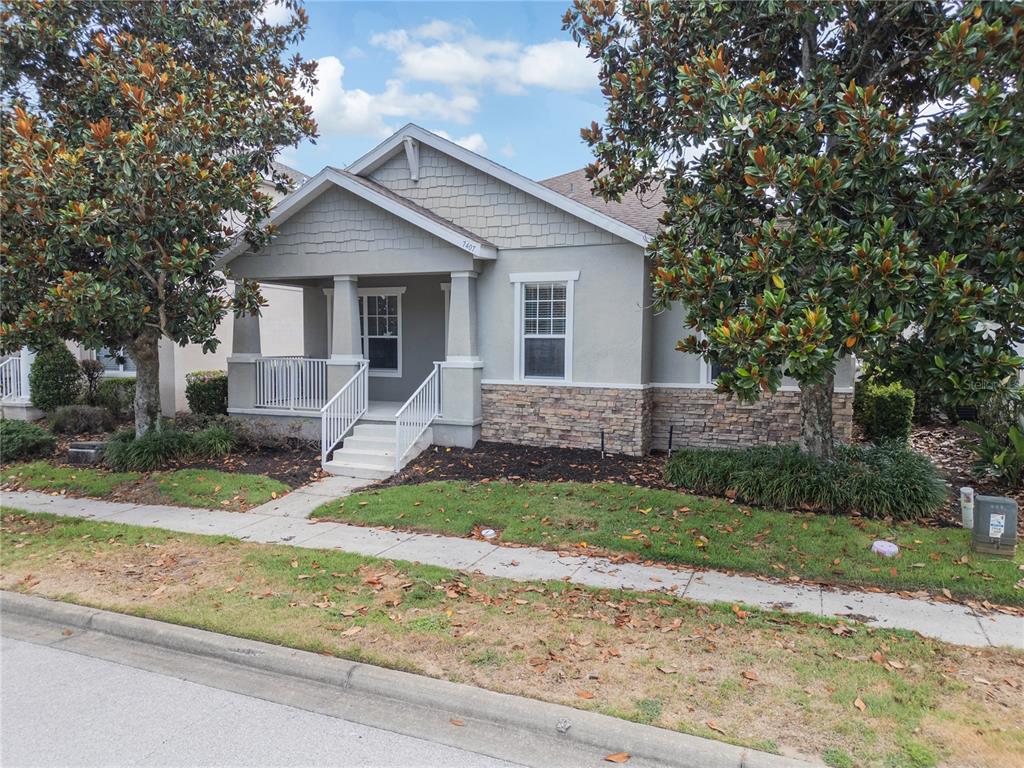 A single-story house with a front porch, stone veneer siding, and two large magnolia trees — 7407 DEVEREAUX STREET, REUNION, FL
