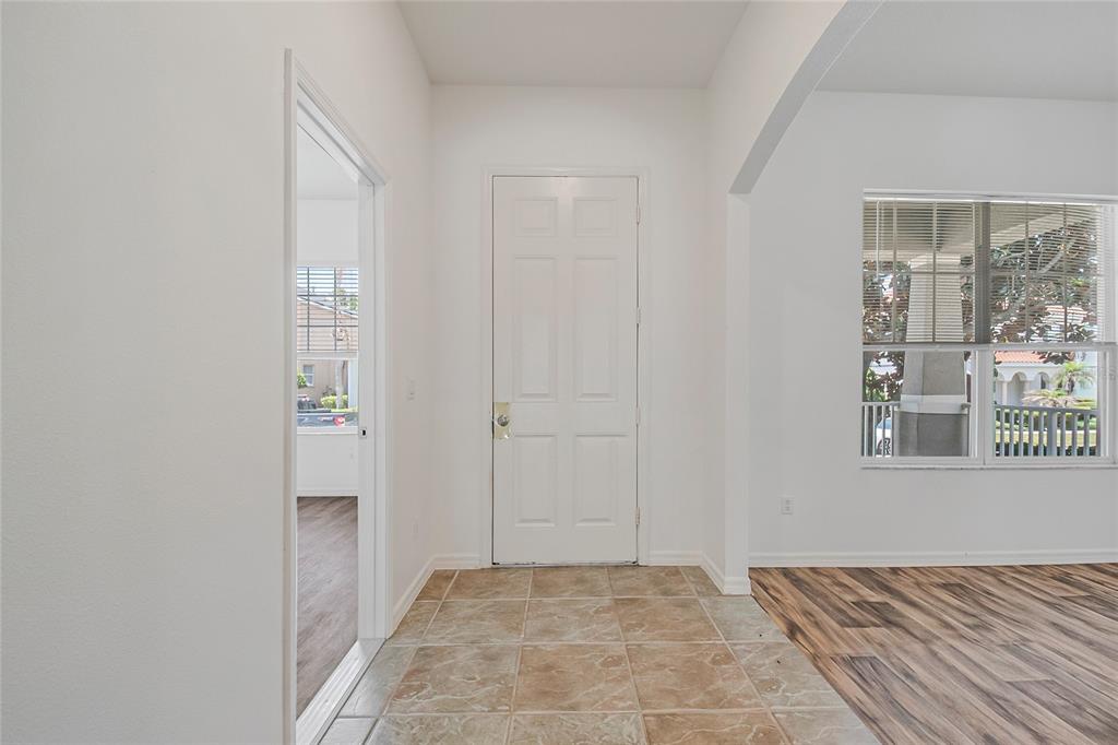 An entryway with tiled flooring, a white front door, and a view into another room — 7407 DEVEREAUX STREET, REUNION, FL