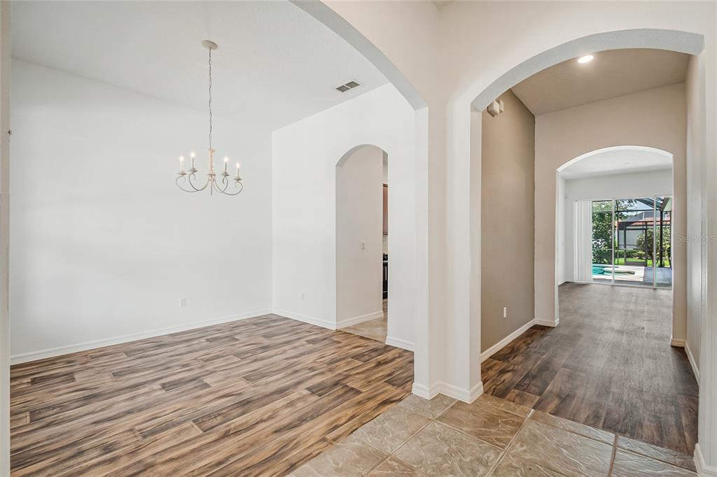 A dining room with wood-look flooring and a chandelier leads to a tiled entryway — 7407 DEVEREAUX STREET, REUNION, FL