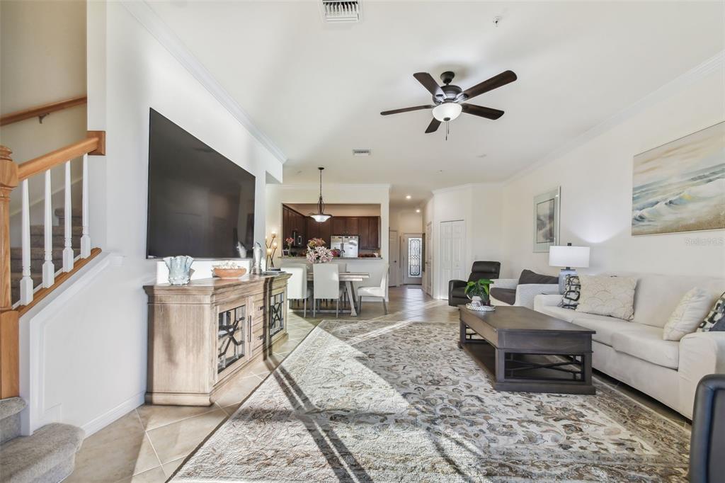 A living room with a large television, wooden console, area rug, and adjacent dining area — 20252 LAGENTE CIRCLE, VENICE, FL