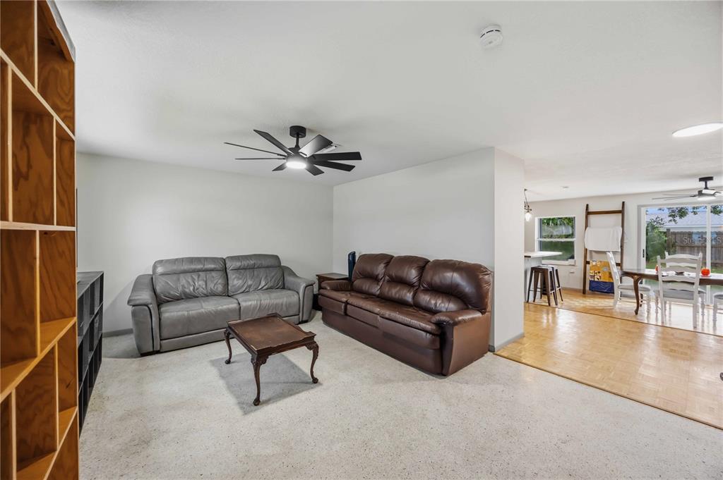 A living room with two leather sofas, a coffee table, and an adjacent dining area — 21298 MIDWAY BOULEVARD, PORT CHARLOTTE, FL