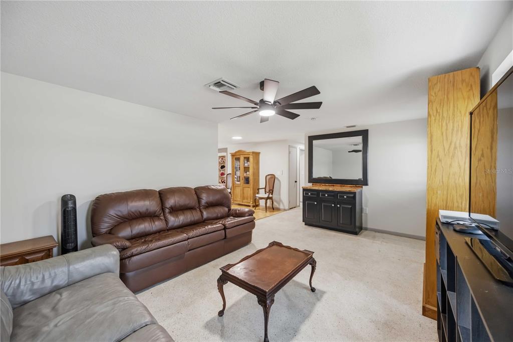A living room features a brown leather sofa, a coffee table, and a black sideboard — 21298 MIDWAY BOULEVARD, PORT CHARLOTTE, FL