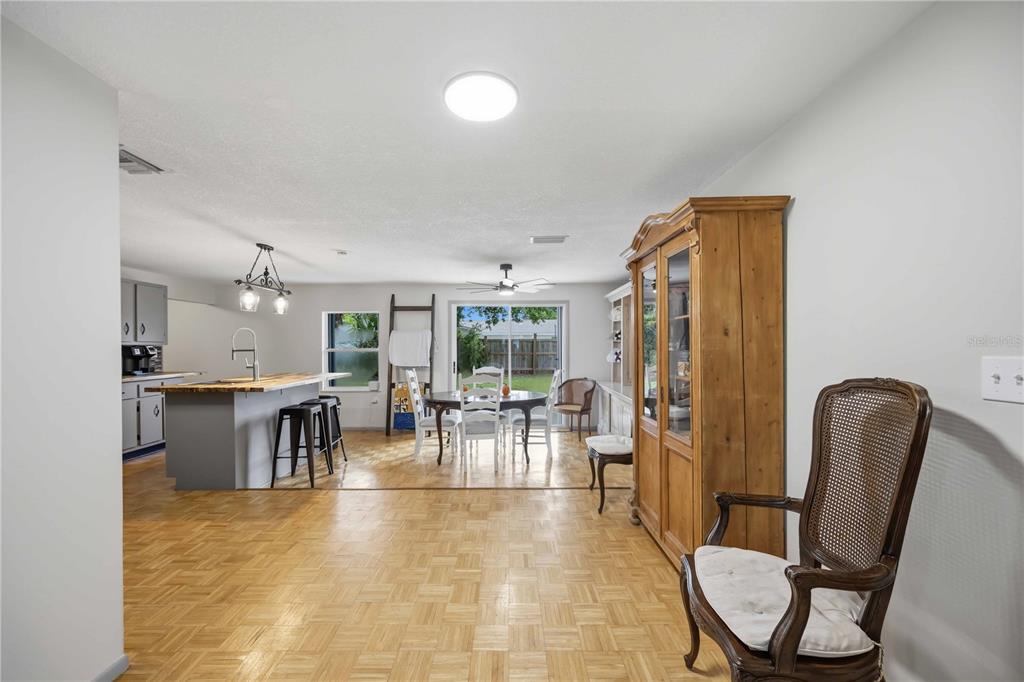 An open-concept kitchen and dining area features wood parquet flooring and a large wooden hutch — 21298 MIDWAY BOULEVARD, PORT CHARLOTTE, FL
