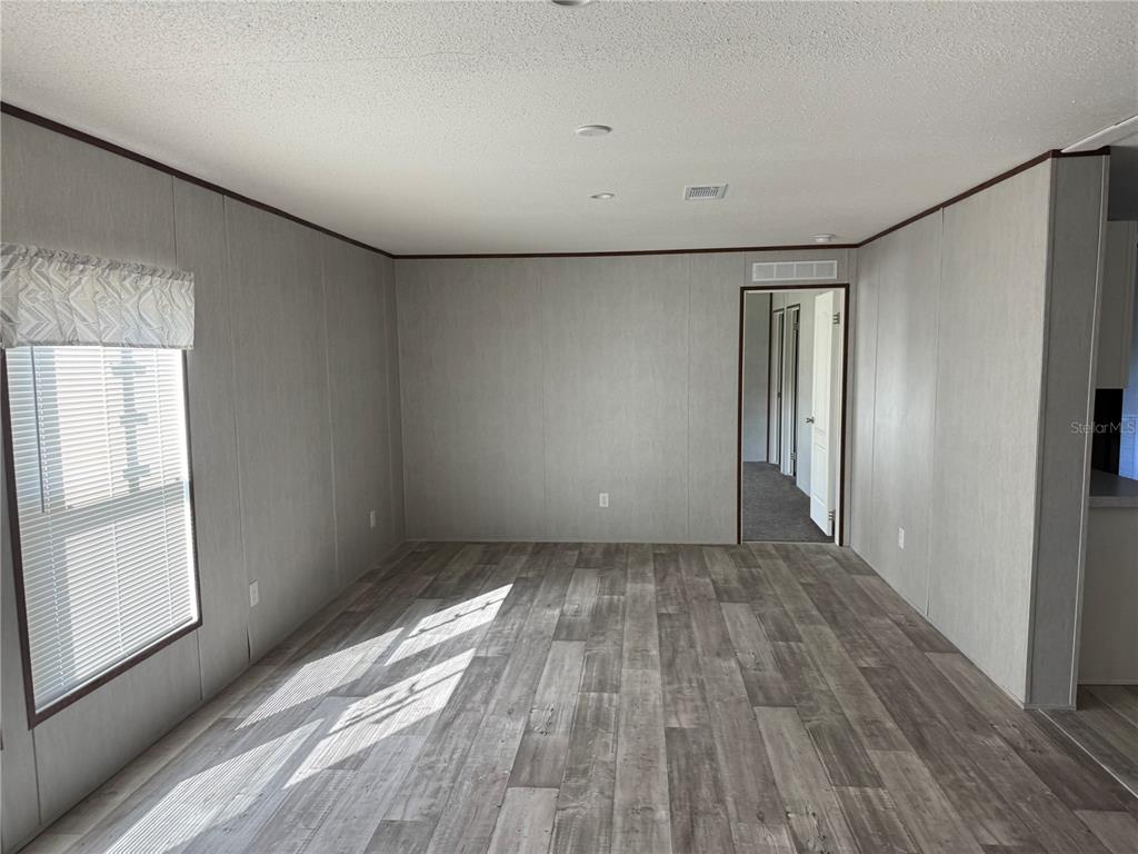 An empty room features gray wood-look flooring, light gray walls, and a doorway leading elsewhere — 1561 POE ROAD, LAKE WALES, FL