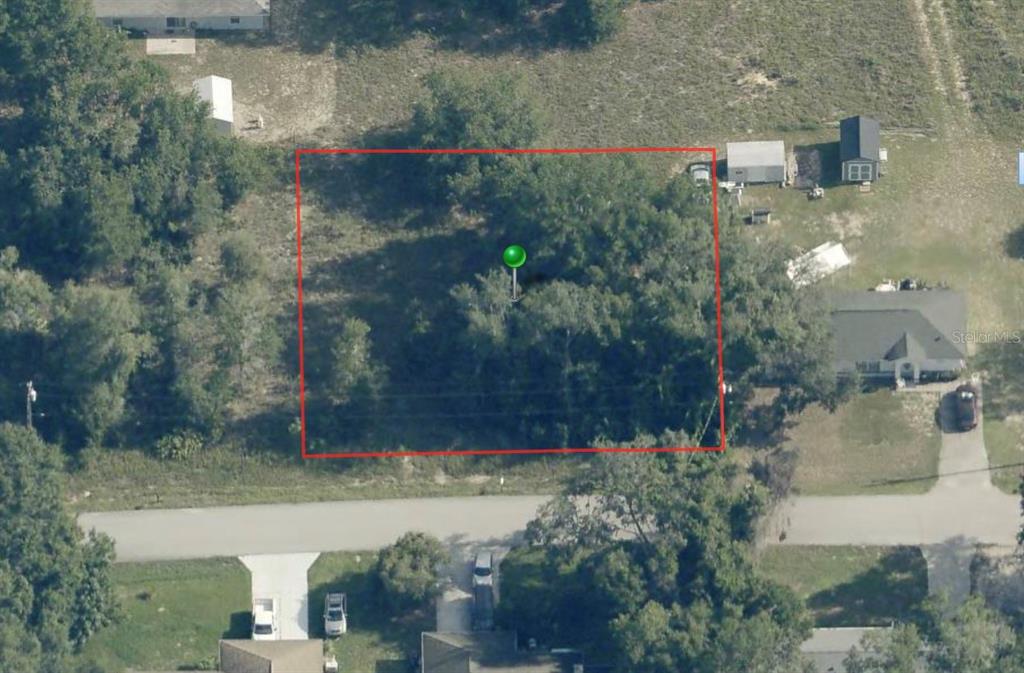 An aerial view shows a rectangular, wooded vacant lot outlined in red along a road — 3943 E SCOTTY STREET, INVERNESS, FL