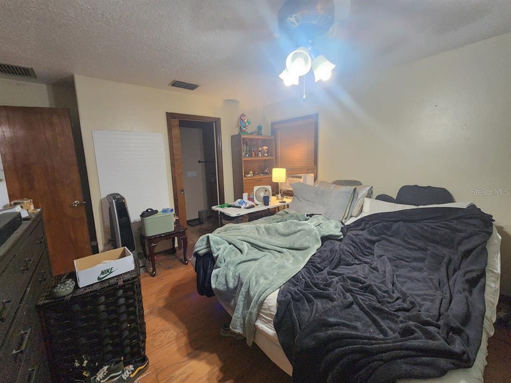 A bedroom features a bed with dark and light blankets, a ceiling fan, and wood flooring — 2407 SUMMER HOLLOW DRIVE, AUBURNDALE, FL