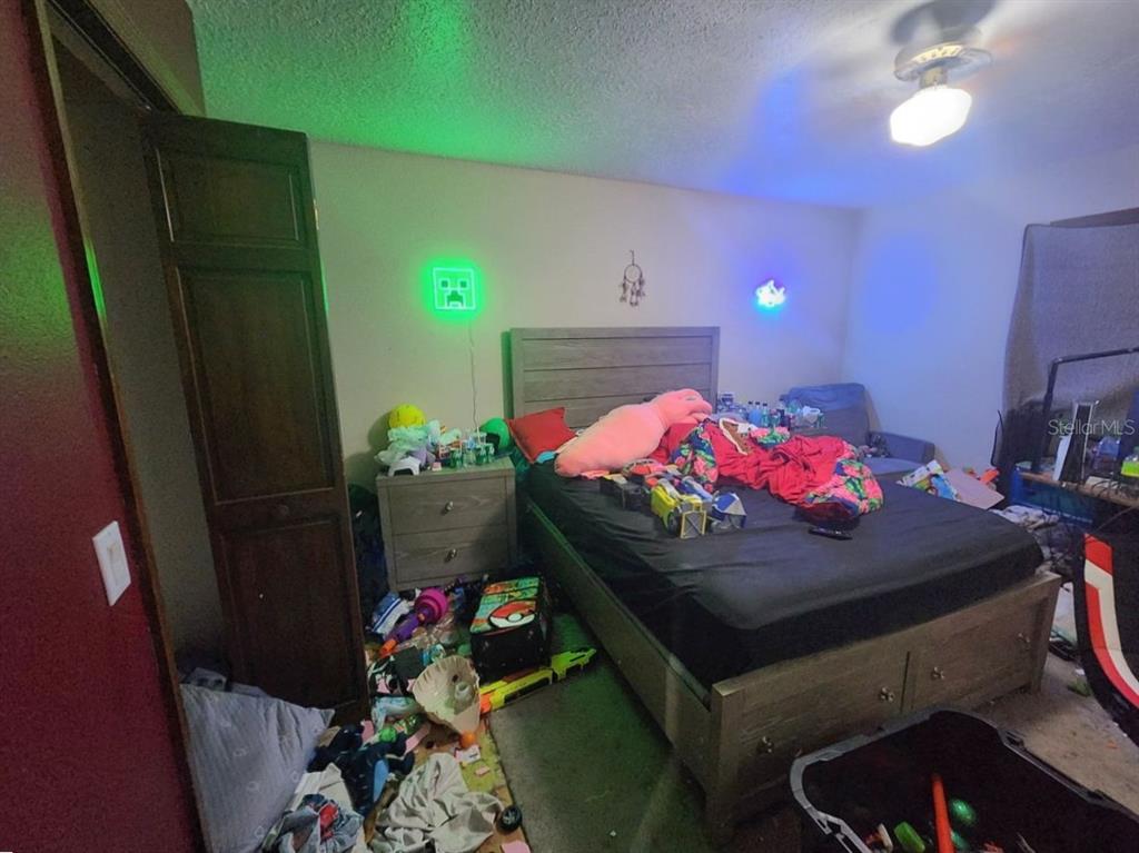 A bedroom with a bed, wooden headboard, nightstand, and various toys scattered on the floor — 2407 SUMMER HOLLOW DRIVE, AUBURNDALE, FL