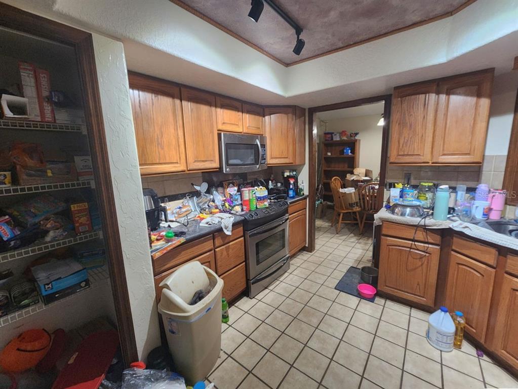 A kitchen with wood cabinets, tile flooring, a stainless steel oven, and a walk-in pantry — 2407 SUMMER HOLLOW DRIVE, AUBURNDALE, FL