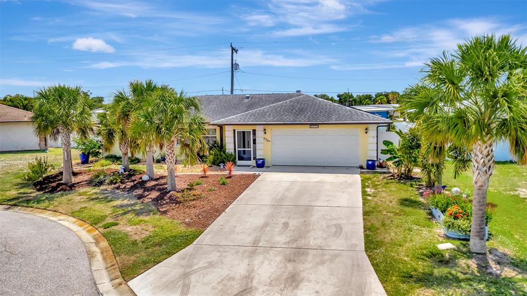 A single-story house with a white garage door, a concrete driveway, and several palm trees — 5729 AUGUSTA CIRCLE, SARASOTA, FL