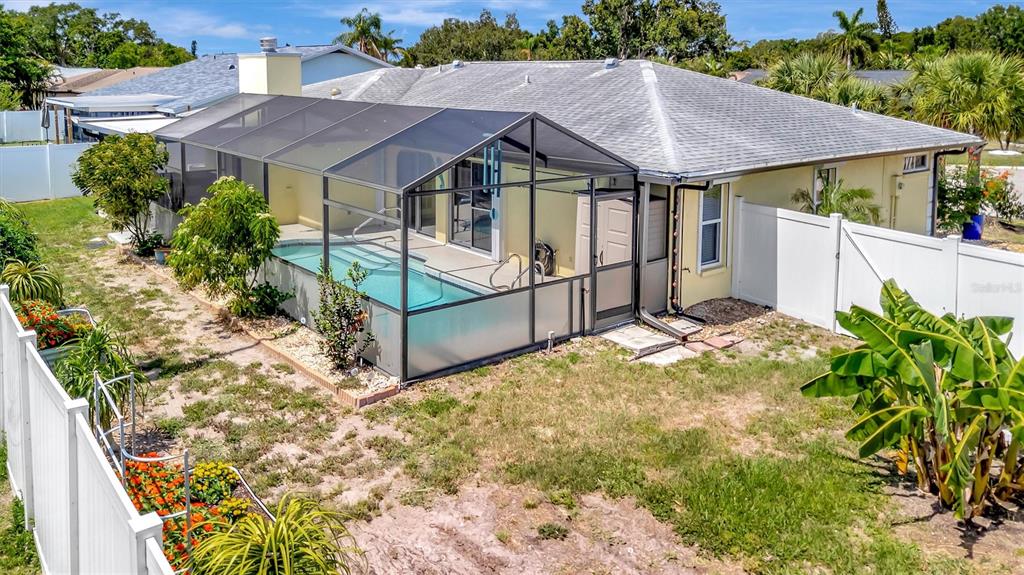 An exterior view of a house with a screened-in pool and a white vinyl fence — 5729 AUGUSTA CIRCLE, SARASOTA, FL