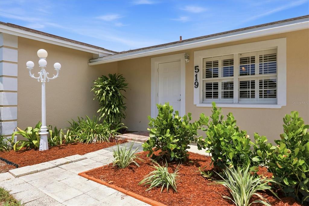 The exterior of a house features a white door, a window, and a lamp post — 519 65TH AVENUE W, BRADENTON, FL