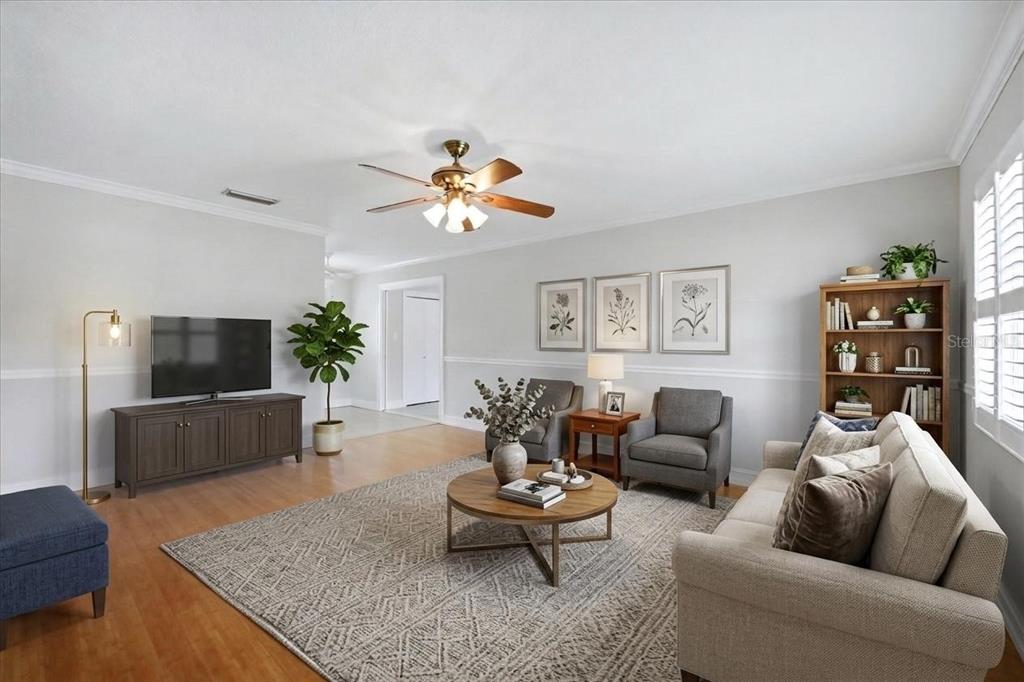 A living room features a beige sofa, two gray armchairs, a television, and a ceiling fan — 519 65TH AVENUE W, BRADENTON, FL