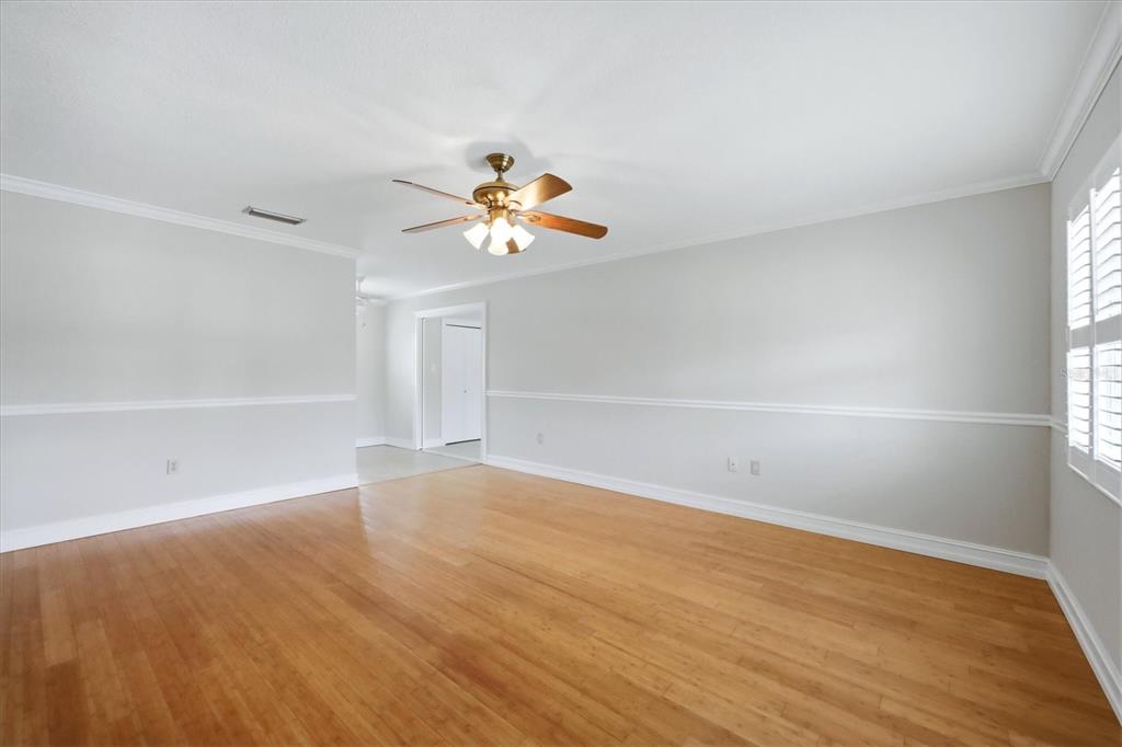 An empty room with light-colored walls, wood flooring, a ceiling fan, and white window shutters — 519 65TH AVENUE W, BRADENTON, FL