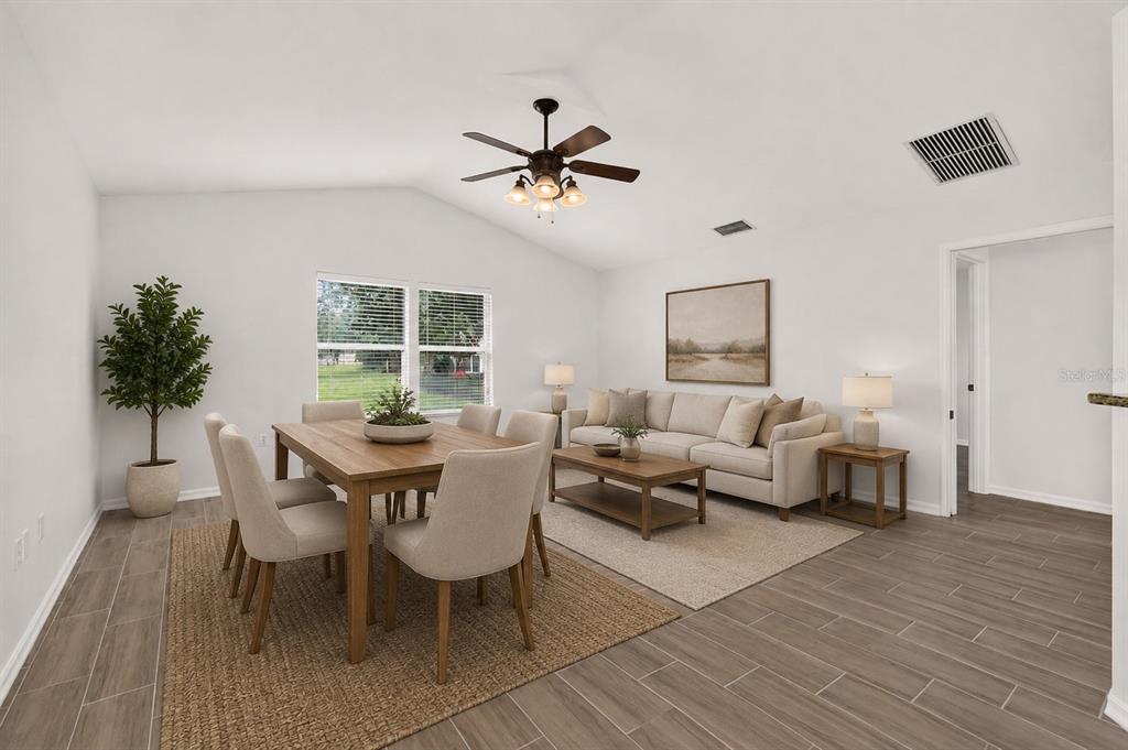 A bright open-concept living and dining area features light wood-look tile flooring and vaulted ceilings — 8120 SW 52ND LANE, GAINESVILLE, FL