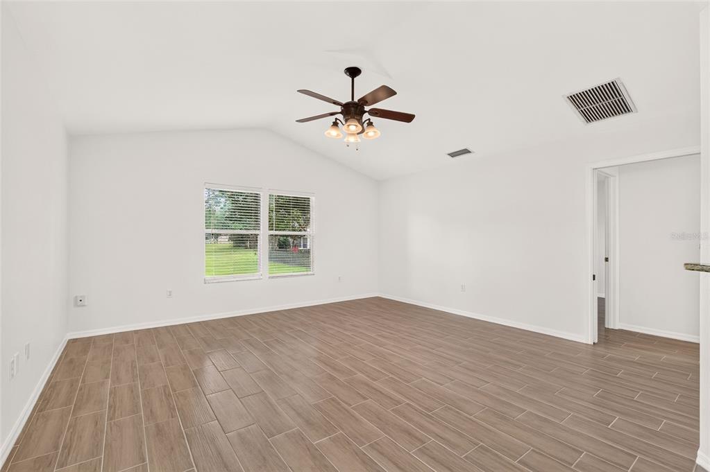 An empty room with white walls, wood-look tile flooring, a ceiling fan, and a window — 8120 SW 52ND LANE, GAINESVILLE, FL