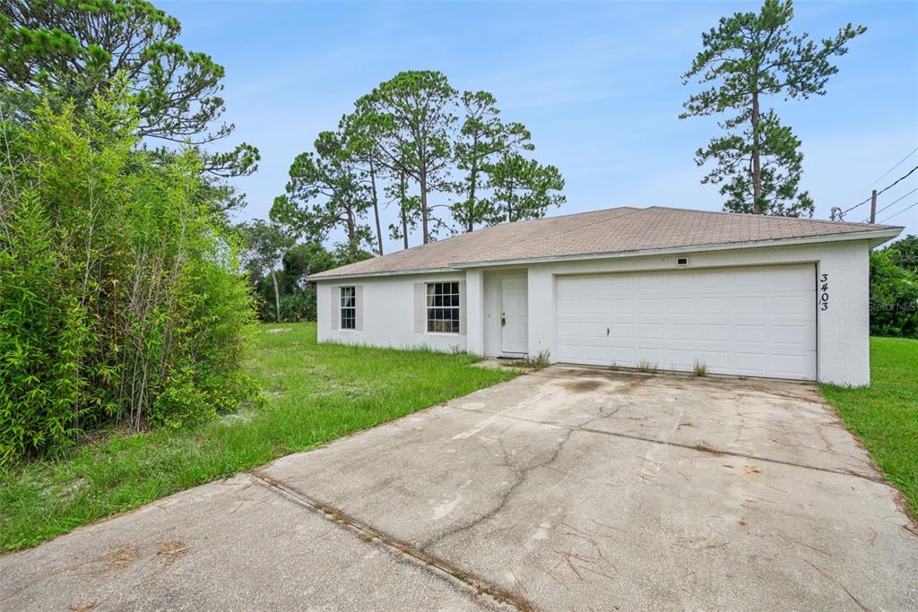 A single-story house with a white stucco exterior, a two-car garage, and a concrete driveway — 3403 QUEEN PALM DRIVE, EDGEWATER, FL
