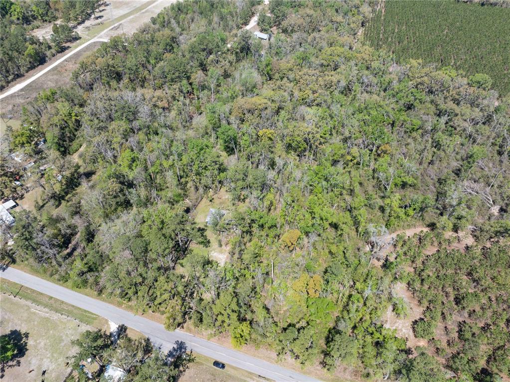 An aerial view shows a wooded lot with a small house and a paved road — 9311 86TH STREET, LIVE OAK, FL