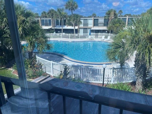 A view from a balcony overlooking a swimming pool surrounded by palm trees and buildings — 5500 OCEAN SHORE BOULEVARD UNIT UT42, ORMOND BEACH, FL