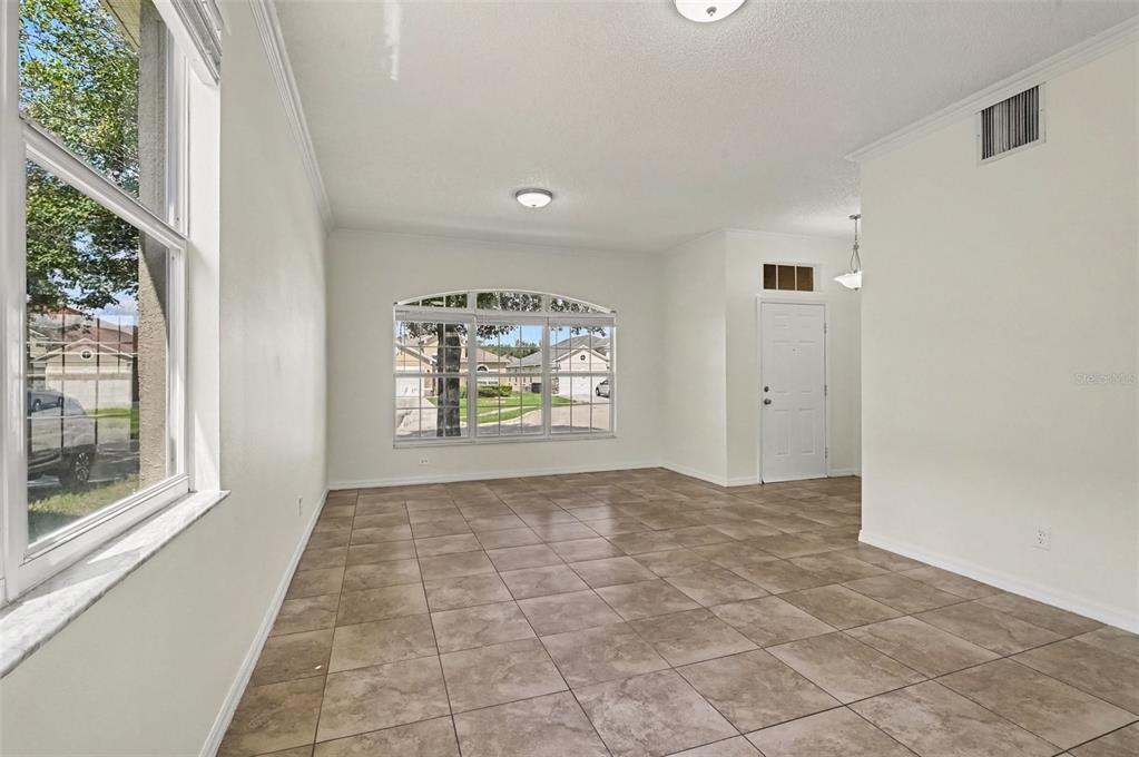 An empty room with beige tile flooring, white walls, and a large arched window — 14513 KAISER COURT, ORLANDO, FL