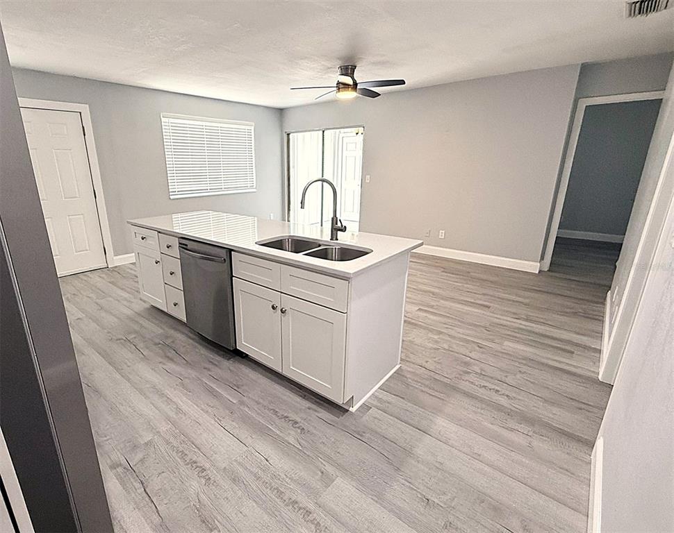 A kitchen with white cabinets, stainless steel appliances, and a center island, featuring wood-look flooring — 1231 ILLINOIS AVENUE UNIT 1, PALM HARBOR, FL