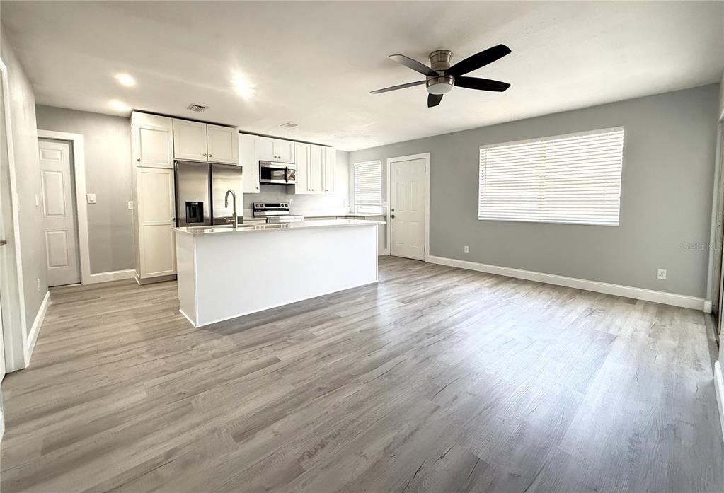 A kitchen with white cabinets, a central island, and light wood-look flooring — 1231 ILLINOIS AVENUE UNIT 1, PALM HARBOR, FL