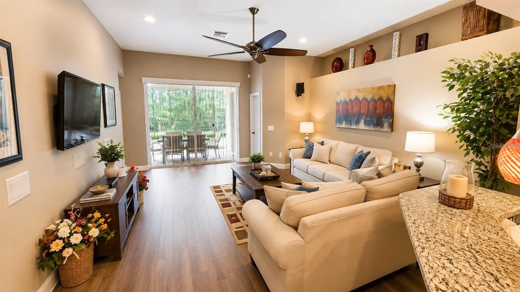 A living room features a beige sofa, a coffee table, and a sliding glass door — 4428 HAVELOCKE DRIVE, LAND O LAKES, FL