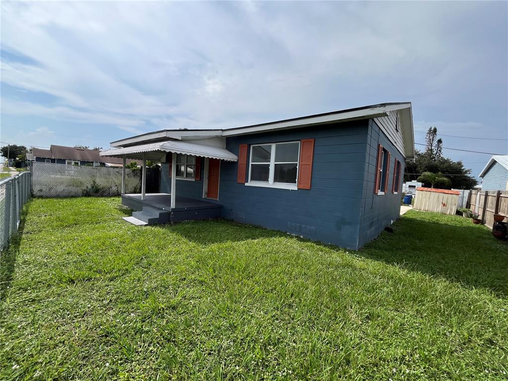 A blue house exterior features a covered porch with a white awning and orange shutters — 1206 E CANAL STREET, MULBERRY, FL