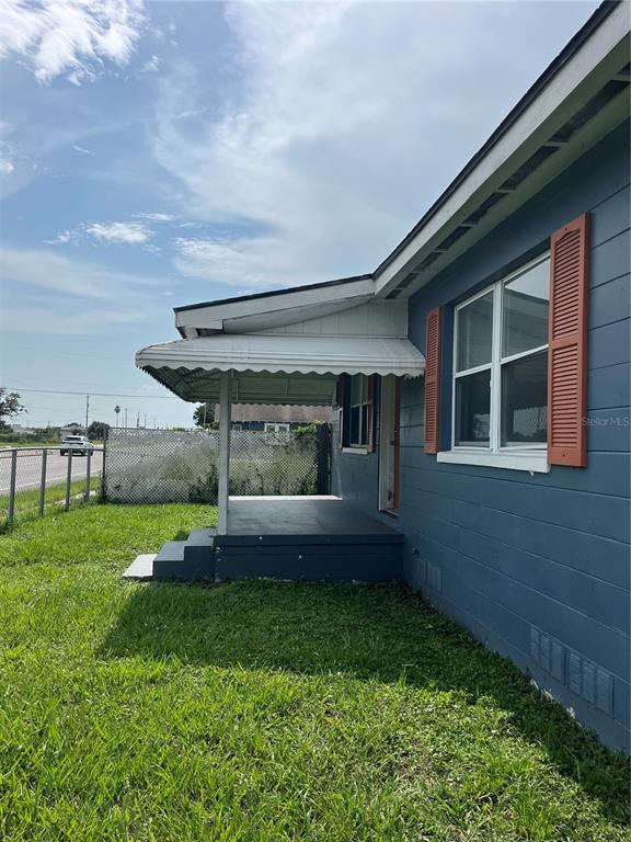 A blue single-story house with orange shutters and a covered front porch sits on grass — 1206 E CANAL STREET, MULBERRY, FL