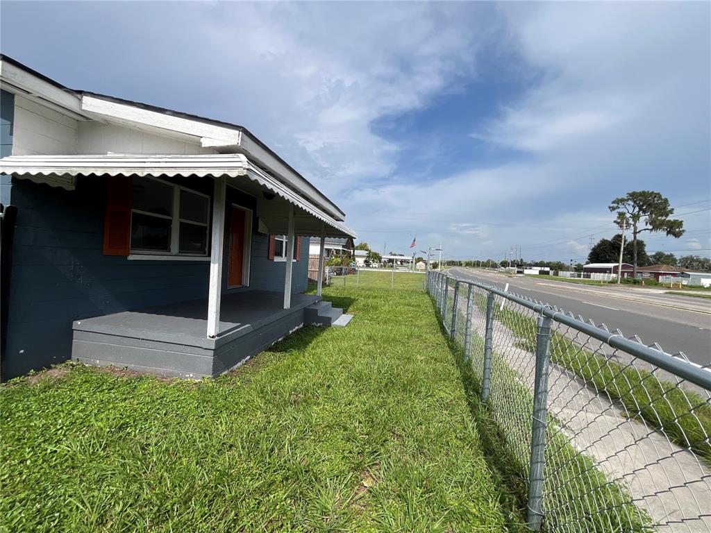 A blue house with a covered porch and a black wooden fence in the yard — 1206 E CANAL STREET, MULBERRY, FL