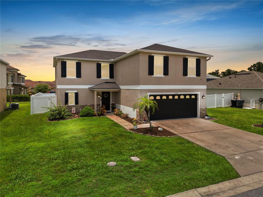 A two-story house with a beige stucco exterior, dark shutters, and a two-car garage — 4188 FESTIVAL POINTE BOULEVARD, MULBERRY, FL