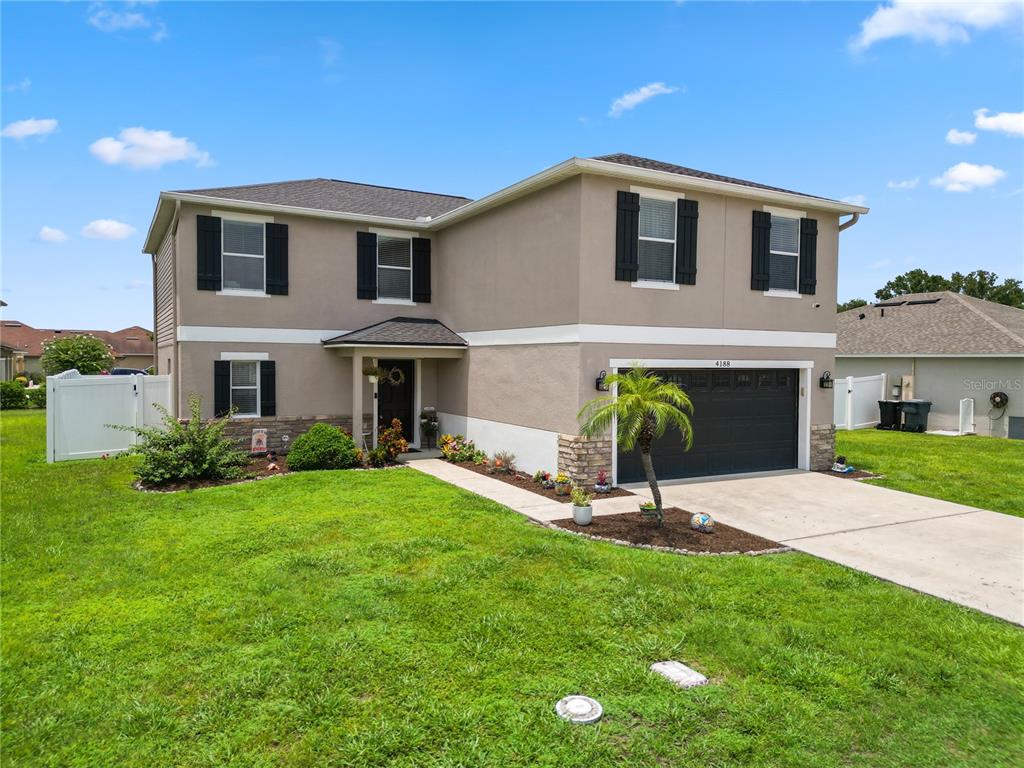 A two-story suburban house with a dark garage door and a concrete driveway — 4188 FESTIVAL POINTE BOULEVARD, MULBERRY, FL