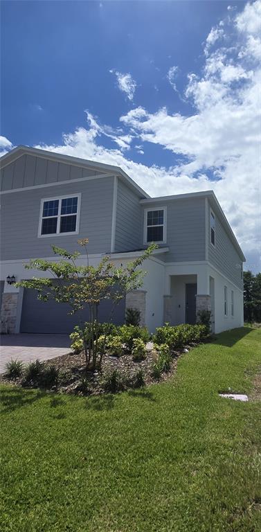 A two-story house with gray horizontal siding, a stone-accented garage, and a landscaped front yard — 2536 STARRY POINT, ST CLOUD, FL
