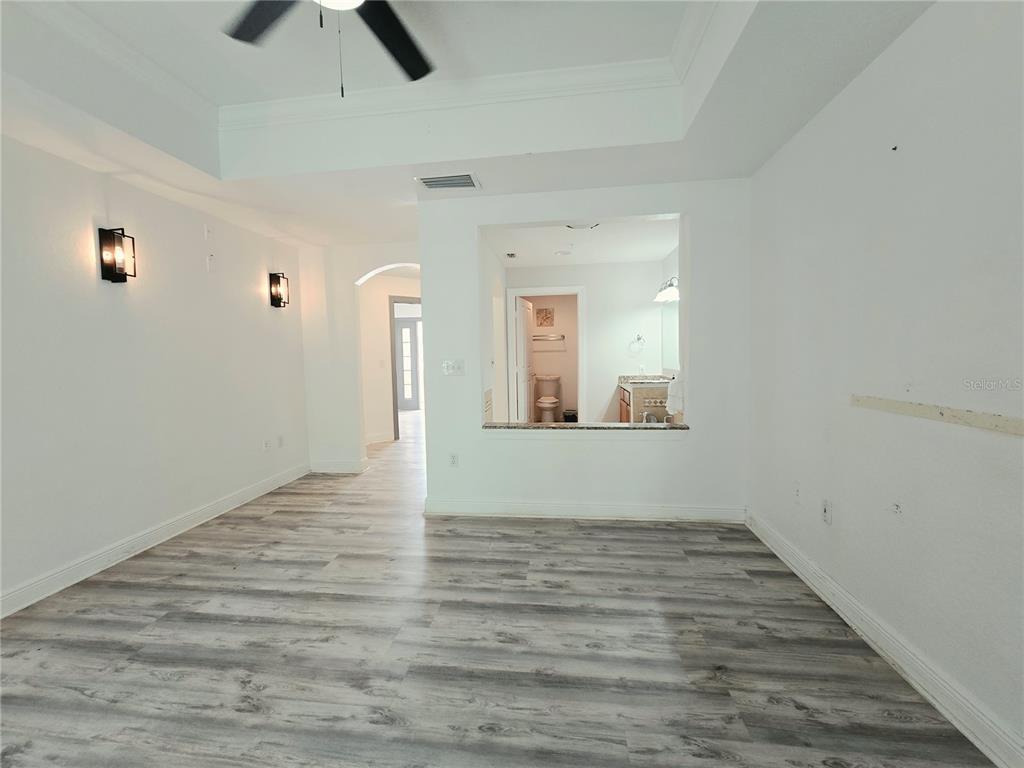 A living room with light wood floors, a dining area, and a kitchen with dark cabinets — 7510 SEVEN EAGLES WAY, REUNION, FL