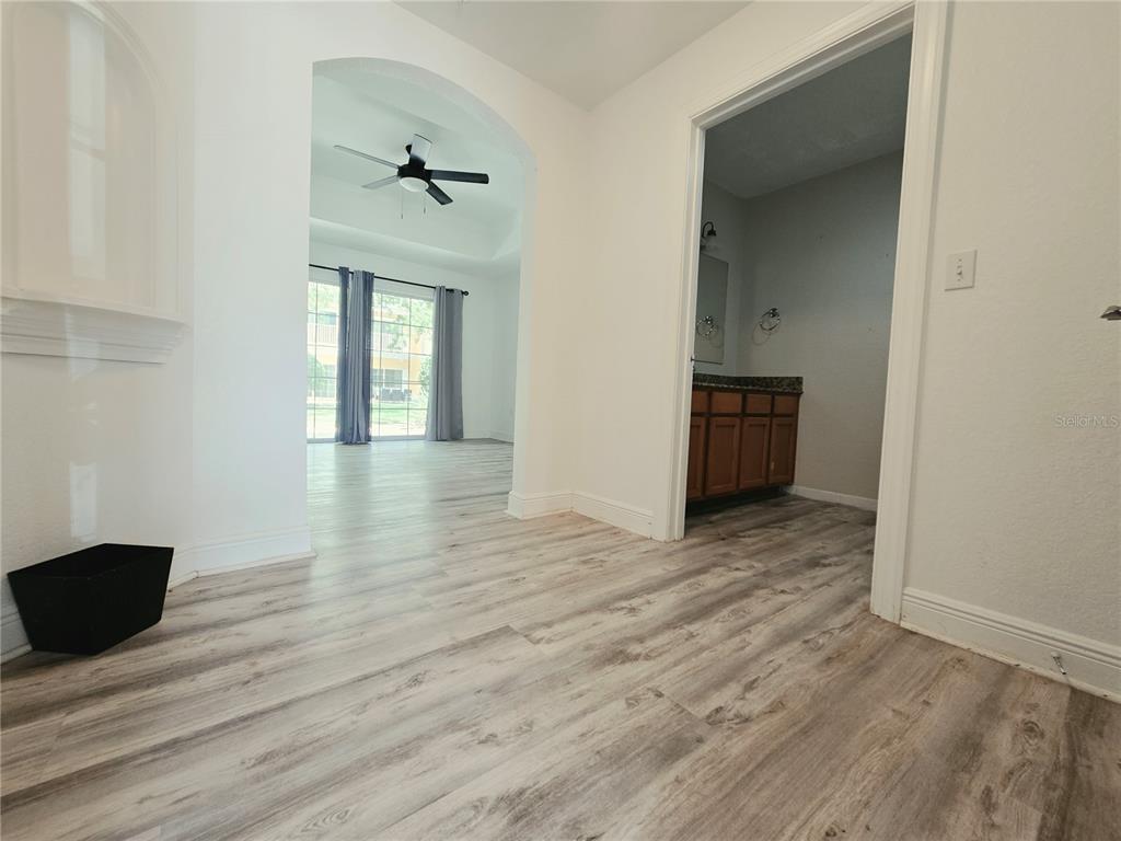 A living and dining area features wood-look flooring, a balcony, and a desk space — 7510 SEVEN EAGLES WAY, REUNION, FL