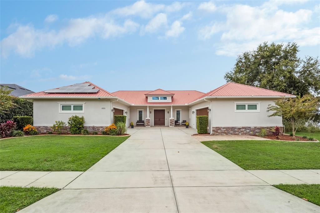 A single-story house with a red metal roof, solar panels, and a concrete driveway — 16909 FLORENCE VIEW DRIVE, MONTVERDE, FL