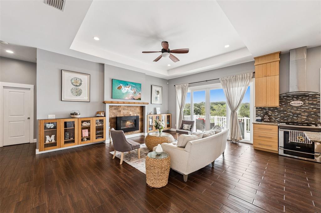 An open-concept living room features a fireplace, wood floors, and a kitchen with wood cabinetry — 16909 FLORENCE VIEW DRIVE, MONTVERDE, FL