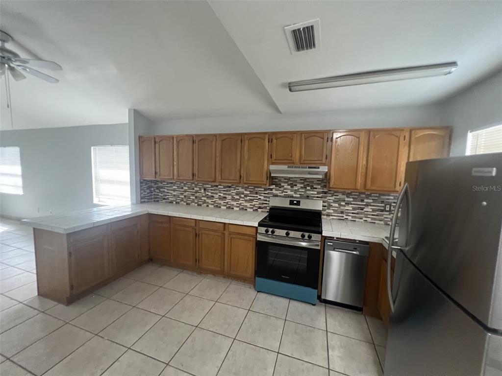 A tan house exterior features a covered patio with tiled flooring and French doors — 4843 BILLY DIRECT LANE, LUTZ, FL