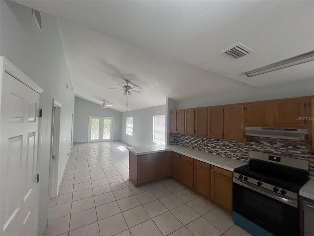 A backyard features a sandy lawn, mature trees, and a weathered wooden privacy fence — 4843 BILLY DIRECT LANE, LUTZ, FL